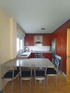 uma cozinha com armários vermelhos, uma mesa e cadeiras em Apartamento cerca de la playa em Finisterre