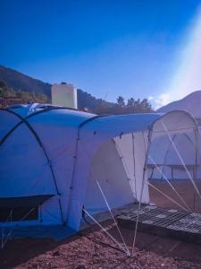 une tente bleue et blanche avec une montagne en arrière-plan dans l'établissement Luxury tent in the middle of nature, 