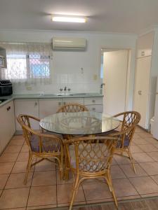 a kitchen with a glass table and some chairs at Beachfront at Silver Sands Hervey Bay in Hervey Bay