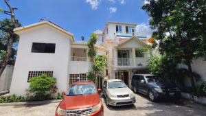 two cars parked in front of a white house at Super Two Bedroom Penthouse in Peguy-Ville in Port-au-Prince