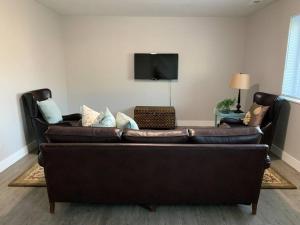 um sofá de couro castanho numa sala de estar com uma televisão em Rooms with a Mountain View em Pleasant Grove