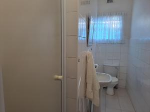 a white bathroom with a toilet and a sink at Iqhayiya Guest House in Durban