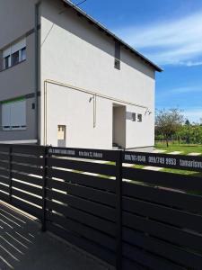 Uma casa branca com uma cerca preta à frente. em Holiday house with a parking space Vukovar, Slavonija - 22809 em Vukovar