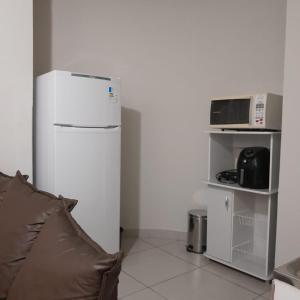 La cuisine est équipée d'un réfrigérateur blanc et d'un four micro-ondes. dans l'établissement Apartamento Inteiro Iguaçu Ipatinga, à Ipatinga