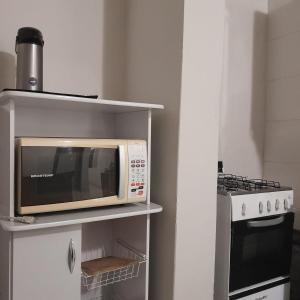 Un four micro-ondes est installé sur une étagère à côté d'une cuisinière. dans l'établissement Apartamento Inteiro Iguaçu Ipatinga, à Ipatinga