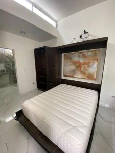 a bedroom with a white bed and a painting on the wall at Loft, Departamento Con cocina, Súper Lujo, Cuarzo in Monterrey