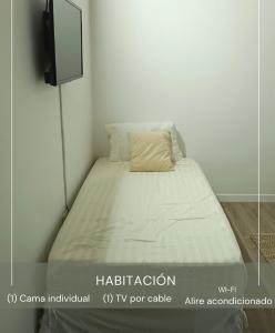 Cama en habitación blanca con almohada en Casa Wadara en La Mira