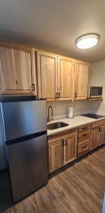a kitchen with a refrigerator and wooden cabinets at Eagle River Lodge in Eagle River