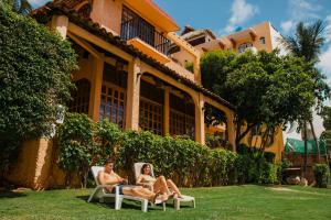 Ein Mann und eine Frau sitzen auf einem Gartenstuhl vor einem Haus. in der Unterkunft Villa Casalet in Puerto Escondido