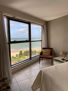 a bedroom with a large window with a view of the ocean at Recife Flats Beach Class Internacional in Recife
