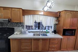 een keuken met houten kasten, een wastafel en een raam bij Adorable Arouca 1BDR Apartment in Arouca