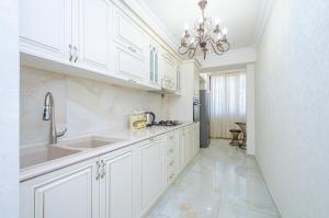 a kitchen with white cabinets and a chandelier at 5A beautiful apartment in the center of the capital photo original in Yerevan +13 photos