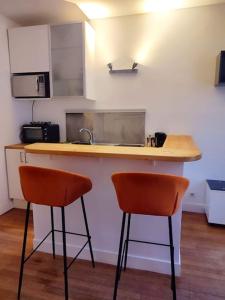 eine Küche mit zwei orangenen Stühlen an der Theke in der Unterkunft Cocon urbain aux portes de Paris/parc Montsouris in Montrouge