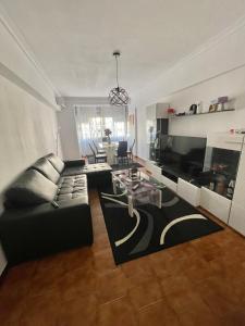 Quarto de Casal Acolhedor في Laranjeira: غرفة معيشة مع أريكة سوداء وطاولة
