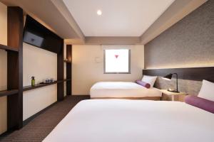 a hotel room with two beds and a window at Doutonbori Crystal Hotel Ⅱ in Osaka