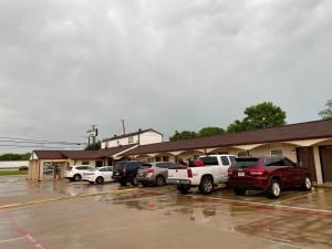 eine Gruppe von Autos, die auf einem Parkplatz geparkt sind in der Unterkunft Ankur Inn Motel in Dallas