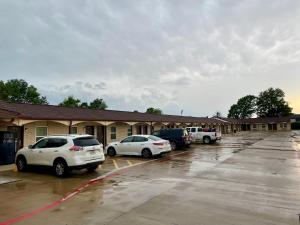dwa samochody zaparkowane na parkingu przed motelem w obiekcie Ankur Inn Motel w mieście Dallas