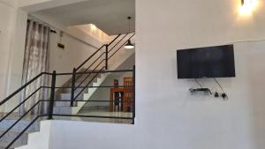 uma televisão de ecrã plano pendurada numa parede ao lado de uma escada em The Leisure Homestay Ella Bandarawela em Bandarawela