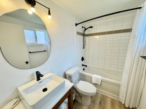 een badkamer met een wastafel, een toilet en een spiegel bij Ukee Peninsula Motel in Ucluelet