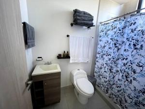 y baño con aseo y cortina de ducha. en Entire apartment with unique view at the best location, en Monterrey