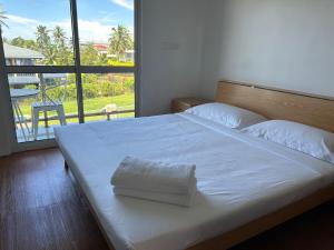 um quarto com uma cama branca e uma grande janela em Easy Apt em Suva