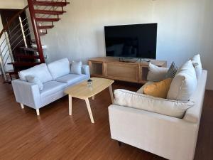 uma sala de estar com 2 sofás e uma televisão de ecrã plano em Easy Apt em Suva