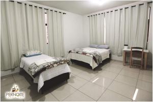sypialnia z 2 łóżkami, stołem i biurkiem w obiekcie Hotel pernoite w mieście Pato Branco