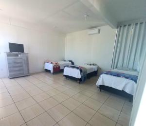 een kamer met drie bedden en een tv. bij Hotel pernoite in Pato Branco