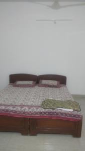 ein Bett mit einem Holzrahmen und Kissen darauf in der Unterkunft Gardenia Groove Villa, Ramky Discovery City in Maisaram