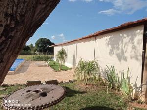 un grand pneu assis dans l'herbe à côté d'un bâtiment dans l'établissement Chácara Urbana Quiosque Canto do Curió, à Araxá