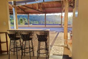 uma cozinha com um bar com quatro bancos em Chácara Urbana Quiosque Canto do Curió em Araxá