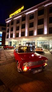 un viejo coche rojo estacionado frente a un edificio en KANYON VADİ HOTEL, en Bostanbükü