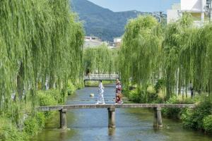 two women walking across a bridge over a river at OMO5 Kyoto Sanjo by Hoshino Resorts in Kyoto