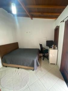 a bedroom with a bed and a desk and a chair at Casa temporada em Paraty RJ in Paraty