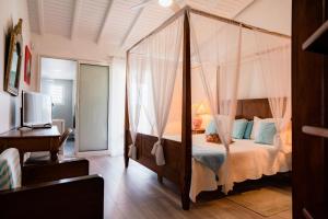 a bedroom with a canopy bed and a desk at La Source Guest House in Orient Bay +58 photos