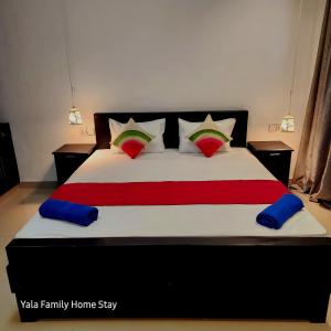 a bedroom with a large bed with red and blue pillows at YALA FAMILY HOMESTAY in Tissamaharama