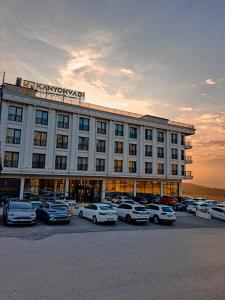 un gran edificio con coches estacionados en un estacionamiento en KANYON VADİ HOTEL, en Bostanbükü