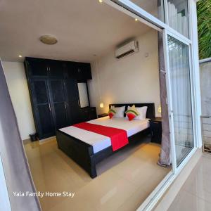 a bedroom with a bed and a large window at YALA FAMILY HOMESTAY in Tissamaharama