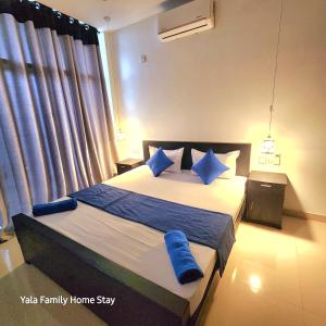 a bedroom with a large bed with blue pillows at YALA FAMILY HOMESTAY in Tissamaharama