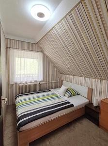 1 dormitorio con 1 cama con pared a rayas en Csillag Vendégház Kiskunmajsa en Kiskunmajsa