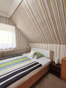 1 dormitorio con 1 cama grande y pared a rayas en Csillag Vendégház Kiskunmajsa en Kiskunmajsa