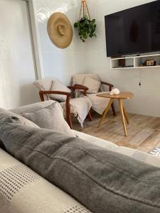 un soggiorno con divano, sedie e TV di Recanto do Mica a Governador Celso Ramos