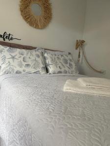 una camera da letto con un letto bianco e uno specchio a parete di Recanto do Mica a Governador Celso Ramos
