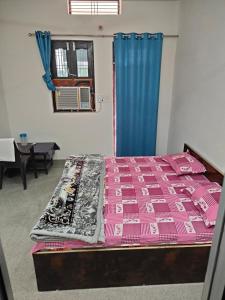 - une chambre avec un lit recouvert d'une couverture rose dans l'établissement Hari Kripa Sadan, à Ayodhya