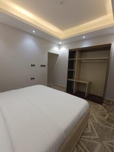 um quarto com uma cama branca e um closet em Maro Hotel em Abha