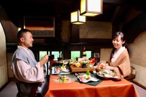 a man and a woman sitting at a table with food at Satonoyu Waraku 13 years or older in Minamioguni