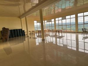 uma grande sala com mesas, cadeiras e janelas em Kirezi Hotel and Conference Center em Bujumbura