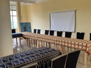 Kirezi Hotel and Conference Center في بوجومبورا: قاعة اجتماعات مع طاولة وكراسي وشاشة