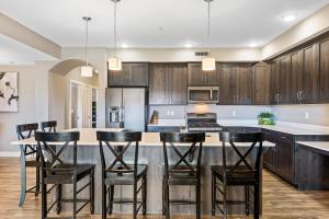 a kitchen with wooden cabinets and a island with bar stools at Sunset Point #W302 condo in St. George