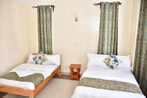 2 camas en una habitación con cortinas en Hope Comfort homes, en Nairobi